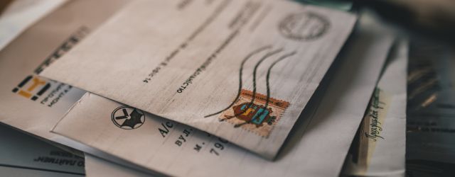 A pile of letters and mailers lie on a table